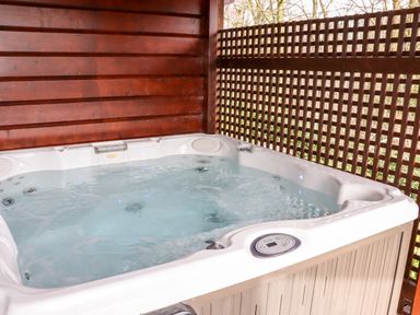 An outdoor hot tub with water and jets surrounded by wooden walls at Watersview Lodge in Rudyard near Leek
