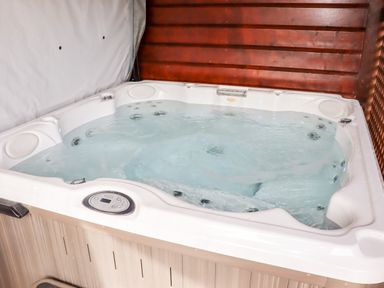 An indoor hot tub filled with water against a wooden wall at Watersview Lodge in Rudyard near Leek