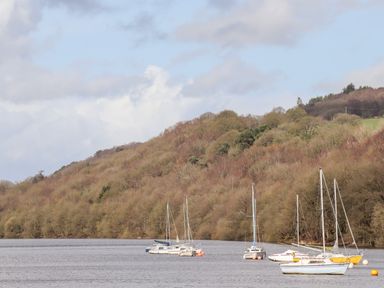 Several sailboats anchored on a river with a wooded hillside in the background at Watersview Lodge in Rudyard near Leek