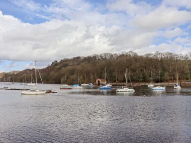 Sailboats moored on a body of water with a forested hill in the background at Watersview Lodge in Rudyard near Leek