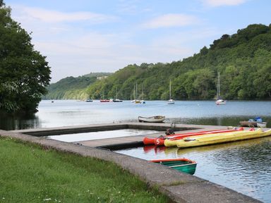 A lakeside view with boats moored at docks and sailboats on the water with trees and hills in the background at Watersview Lodge Rudyard near Leek