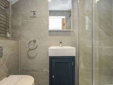 A bathroom with a sink cabinet mirror towel ring toilet and glass shower enclosure at Stargazy Cottage in Praa Sands
