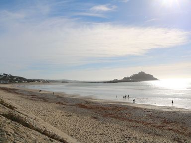A beach with people walking along the shore at Stargazy Cottage in Praa Sands