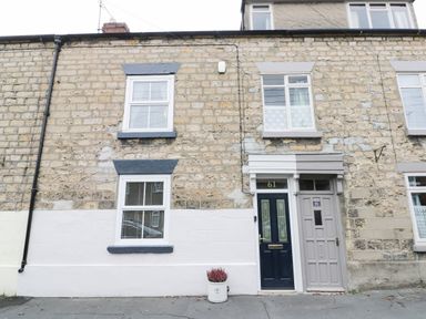 The front of a stone house with two windows above and one below with two doors numbered 60 and 61 and a plant pot on the ground at Potter Hill Cottage in Pickering