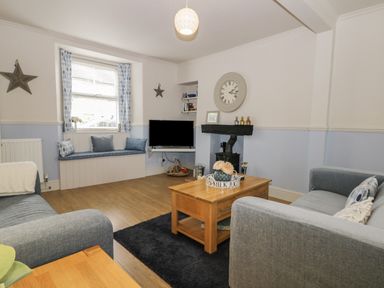 A living room with grey sofas a wooden coffee table a TV and a window seat at Potter Hill Cottage in Pickering