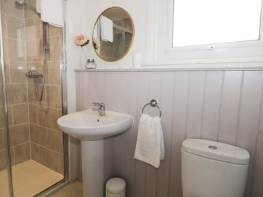 A bathroom with a shower cubicle sink toilet round mirror and towel at Potter Hill Cottage Pickering
