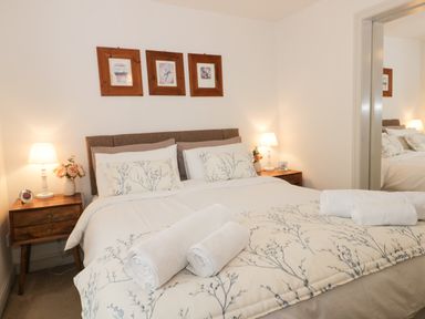 A bedroom with a double bed with floral bedding and rolled towels on the bed at Potter Hill Cottage in Pickering