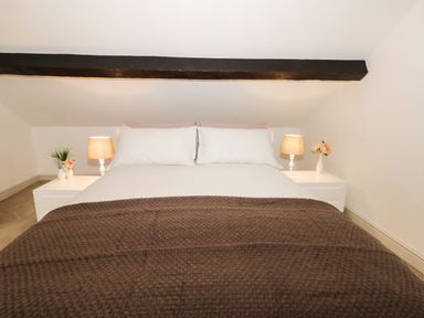 A bed with white pillows and a brown blanket with bedside tables and lamps in a bedroom at Potter Hill Cottage in Pickering