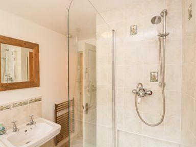 A bathroom with a sink mirror shower and towel rack at Beckfold Cottage in Broughton-In-Furness