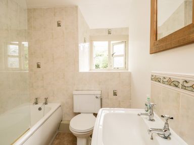 A bathroom with a bathtub toilet sink and tiled walls at Beckfold Cottage in Broughton-In-Furness