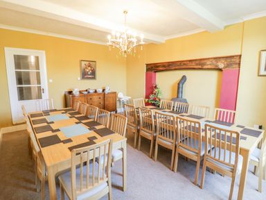 A dining room with two wooden tables and multiple wooden chairs at Squires Rest in Llanfair Caereinion