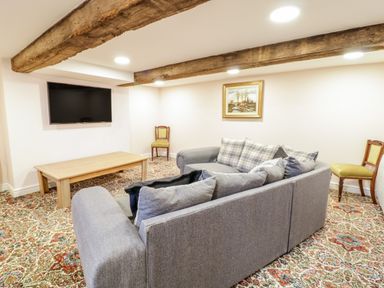 A living room with a grey sofa facing a wall mounted television and a wooden coffee table at Squires Rest in Llanfair Caereinion