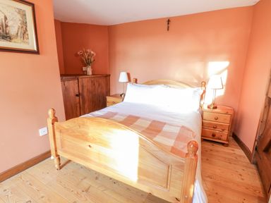 A bedroom with a wooden bed and nightstands with lamps at Squires Rest in Llanfair Caereinion