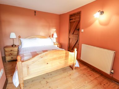 A bedroom with a wooden bed and two bedside tables with lamps at Squires Rest in Llanfair Caereinion