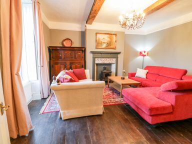 A living room with red and beige sofas wooden coffee table wooden floor and a fireplace at Squires Rest in Llanfair Caereinion