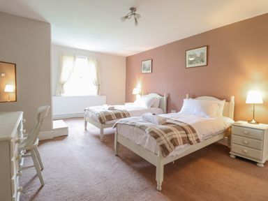 A bedroom with two single beds bedside tables lamps a window and a desk at Squires Rest in Llanfair Caereinion