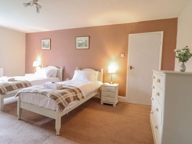 A bedroom with two single beds two nightstands three framed pictures and a chest of drawers at Squires Rest in Llanfair Caereinion