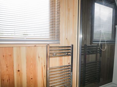 A bathroom with wooden paneling a window with blinds and a chrome towel radiator at Garraidh Ghorm Pod in Conista