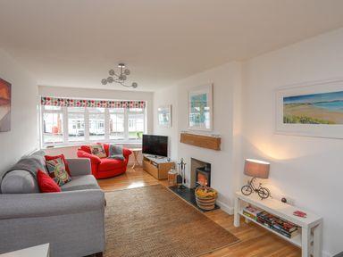 A living room with a grey sofa a red armchair a television and a fireplace at Sisial-Y-Mor in Rhosneigr