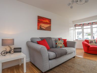 A living room with two sofas red and gray with cushions and a side table with a lamp at Sisial-Y-Mor in Rhosneigr