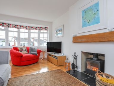 A living room with a red armchair a fireplace and a television at Sisial-Y-Mor in Rhosneigr