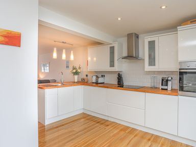 A kitchen with white cabinets wooden countertops and stainless steel appliances at Sisial-Y-Mor in Rhosneigr