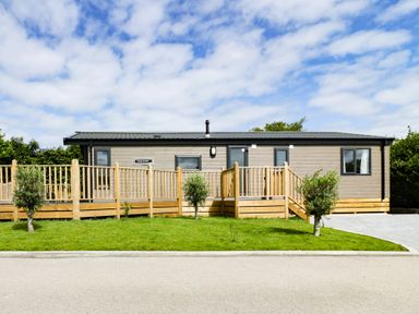 A single-story house with a wooden ramp and steps surrounded by grass at Pinehurst Lodge in St Day