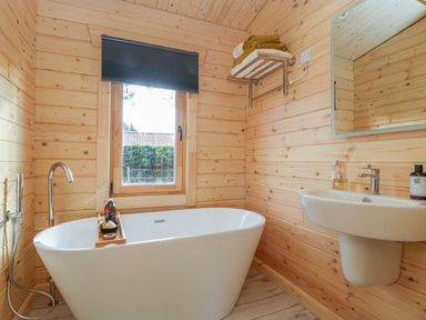 A bathroom with a freestanding bathtub a window a sink a mirror and towels on a rack at Gardener's Lodge in Huby