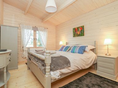 A bedroom with a double bed bedside tables lamps a window with curtains and a wardrobe at Gardener's Lodge in Huby