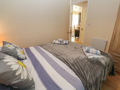 A bedroom with a bed covered in gray and striped bedding with towels placed on it at 11 Tremore in Liskeard