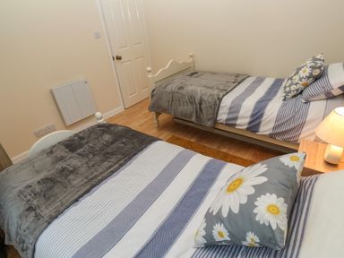 A bedroom with two single beds with striped bedding and daisy pillows at 11 Tremore in Liskeard