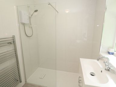 A shower area with glass door a white sink with faucet and a towel radiator at 11 Tremore in Liskeard
