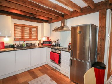 A kitchen with wooden beams white cabinets stainless steel appliances and wooden floor at Honeypot Lodge in Camelford