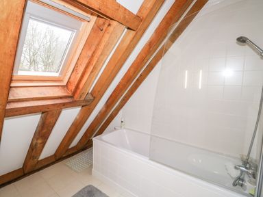 A bathroom with a bathtub shower and a skylight window at Honeypot Lodge in Camelford