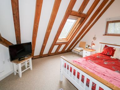 A bedroom with a bed a chair a nightstand and a television at Honeypot Lodge in Camelford