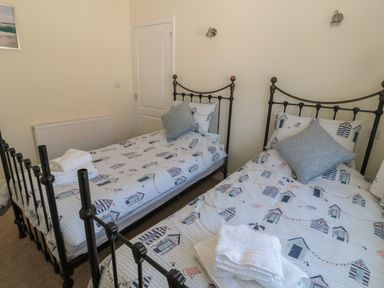 A bedroom with two single beds with patterned bedding and folded towels on them at Hazonleigh in Seahouses