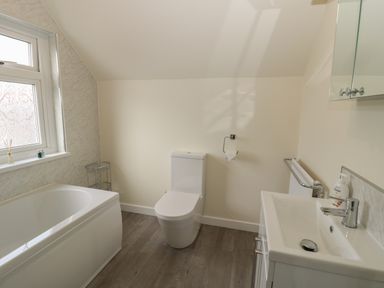 A bathroom with a bathtub toilet sink and window at Hazonleigh in Seahouses