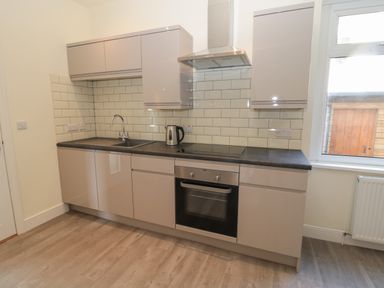 A kitchen with cabinets a sink an electric kettle an oven a stovetop and a window at Hazonleigh in Seahouses