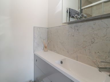 A bathroom sink with a marble backsplash and a diffuser on the countertop at Hazonleigh in Seahouses