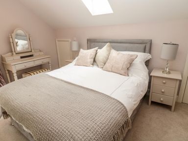 A bedroom with a bed bedside tables lamps and a dressing table at Romsey Lodge in Wark