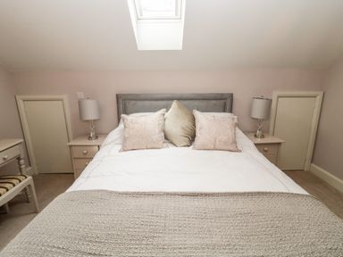 A bedroom with a bed with pillows and bedside tables with lamps under a skylight at Romsey Lodge in Wark