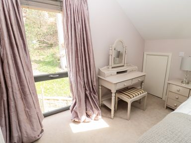 A bedroom corner with a dressing table and stool near a window with curtains at Romsey Lodge in Wark