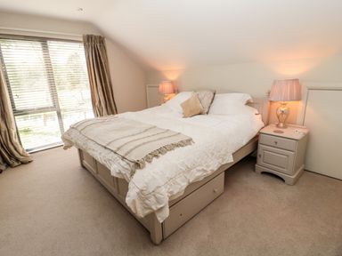 A bedroom with a bed nightstands lamps and a window with curtains at Romsey Lodge in Wark
