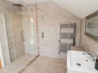 A bathroom with a walk in shower a towel rack a sink with a faucet and a mirror at Romsey Lodge in Wark