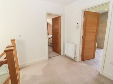 A landing area with carpet flooring wooden doors and staircase railing at Romsey Lodge in Wark