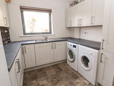 A utility room with a washing machine dryer cabinets and a window at Romsey Lodge in Wark