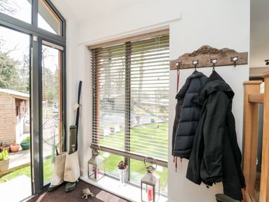 An entryway with coats hanging on a wall hook a pair of boots a fishing net and lanterns on the floor at Romsey Lodge in Wark