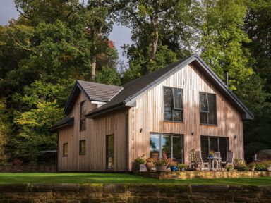 A house with wooden siding and patio furniture at Romsey Lodge in Wark
