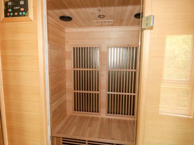 An empty wooden sauna with a bench and control panel at 1 Valley View in Lanreath
