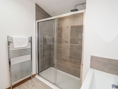 A bathroom with a glass shower enclosure a metal towel rack and partial view of a bathtub at 1 Valley View in Lanreath